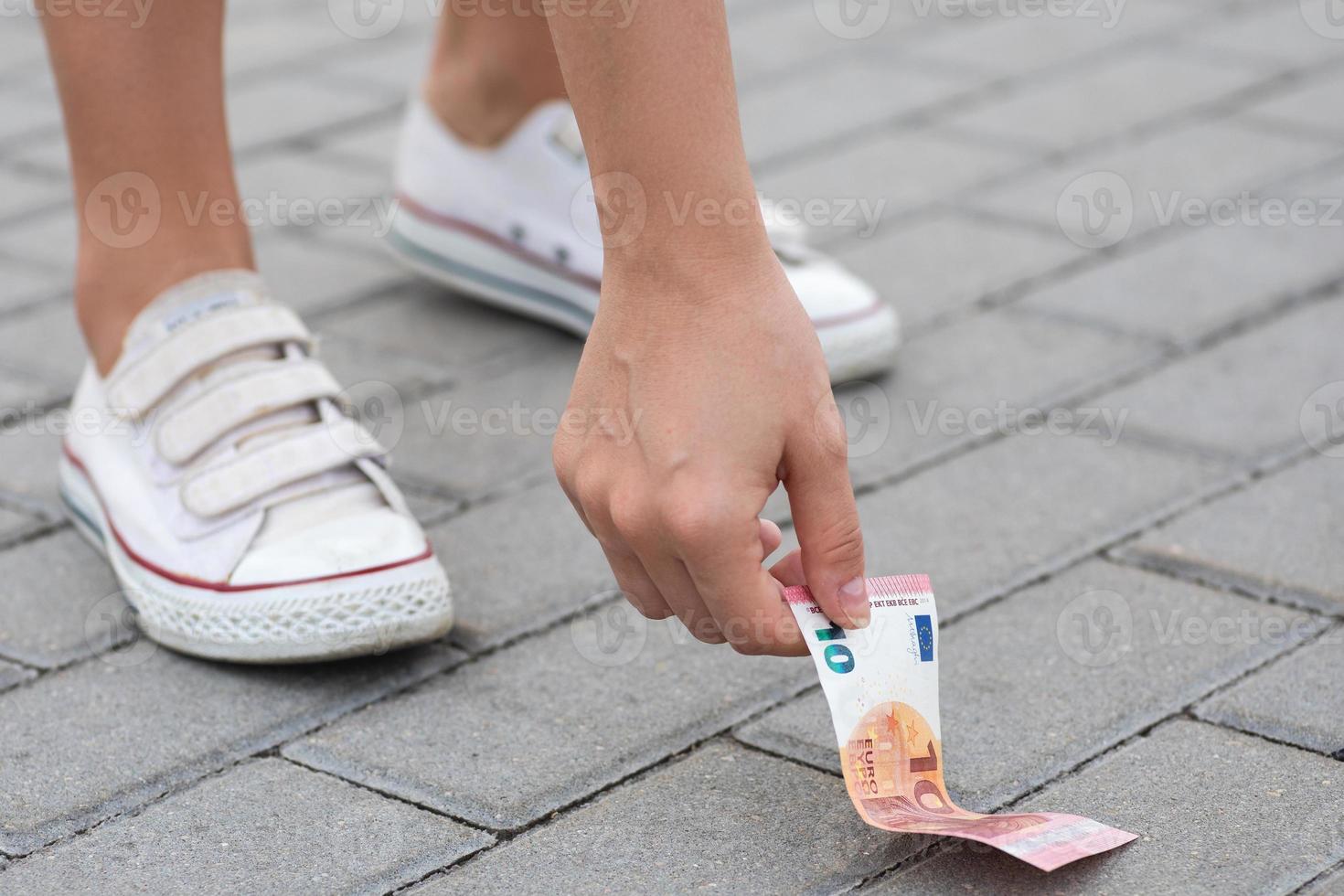 Woman is picking ten euro banknote from the ground photo