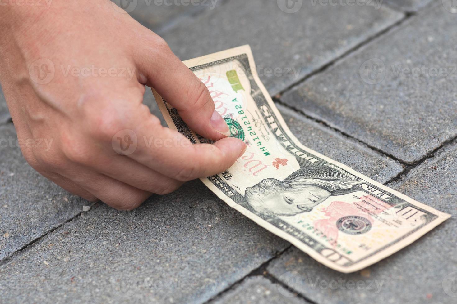 Lucky woman is picking ten dollars banknote from the ground. photo