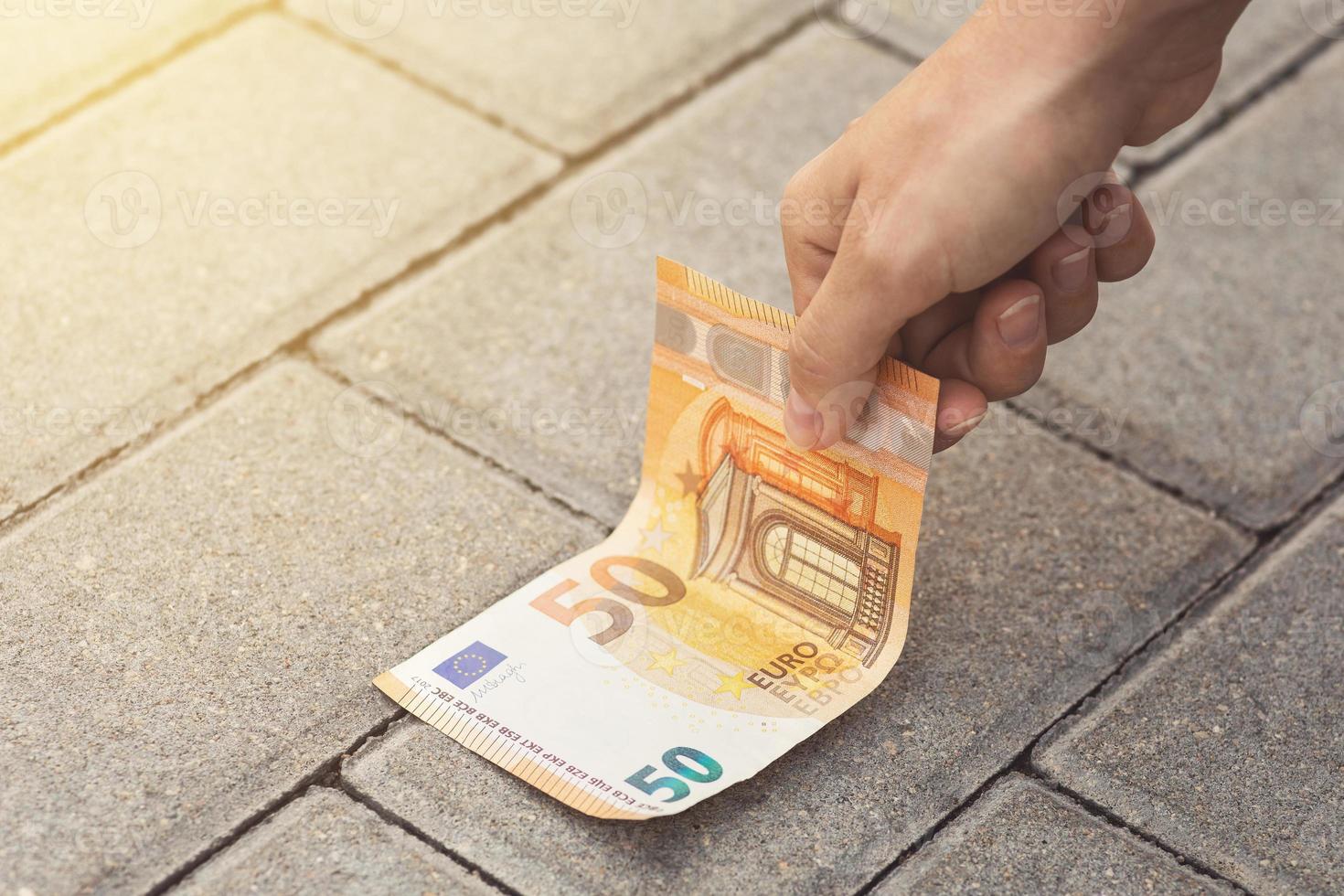 Woman is picking fifty euro banknote from the ground. photo