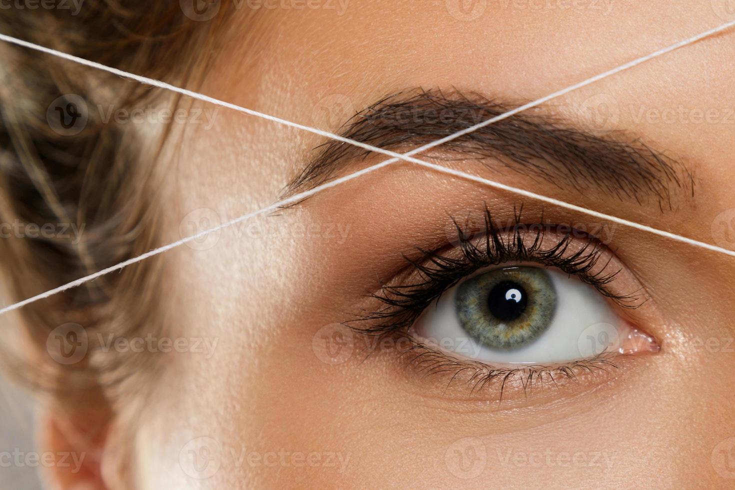 Eyebrow threading - epilation procedure for brow shape correction photo