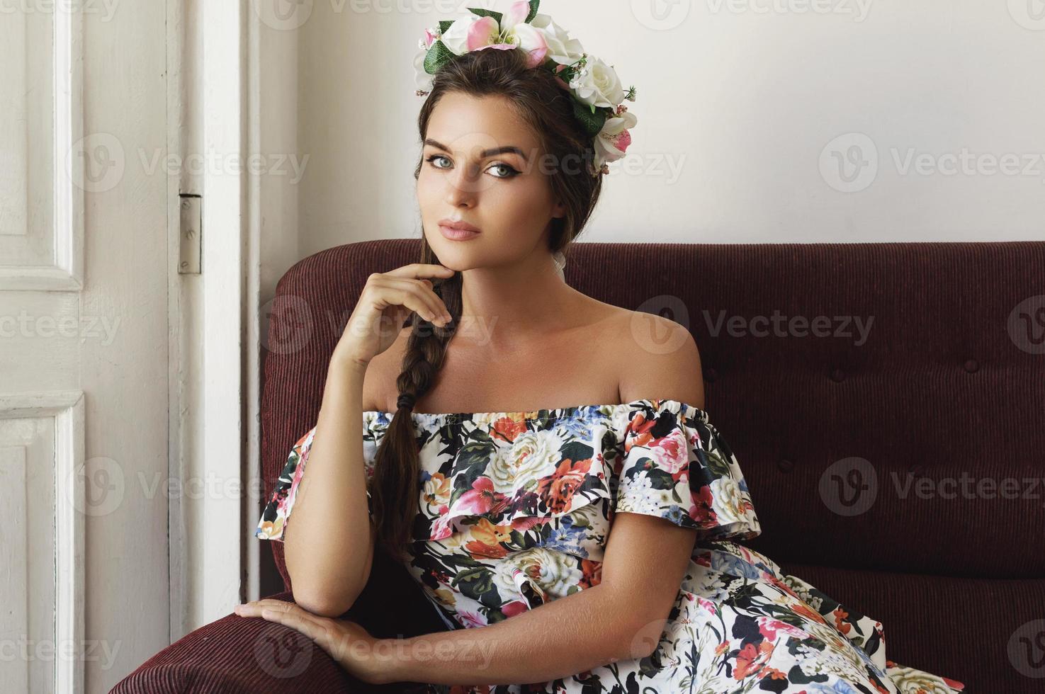 Happy woman in beautiful dress is sitting on the vintage sofa photo