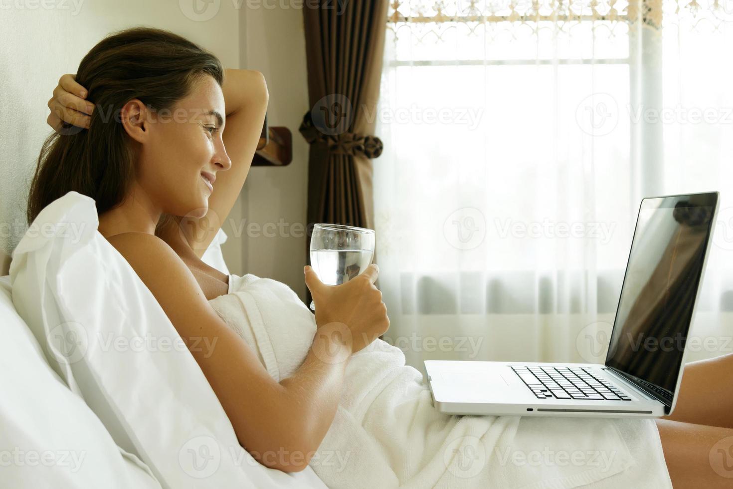 Woman lying on the bed and using laptop pc photo