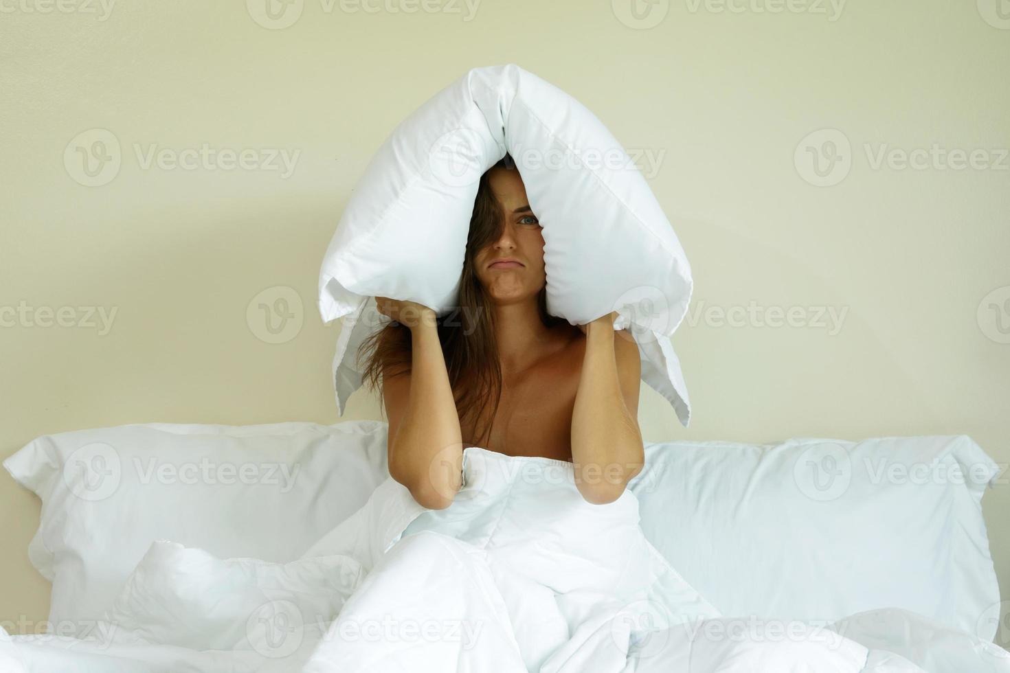 mujer con almohada en la cabeza por el ruido foto
