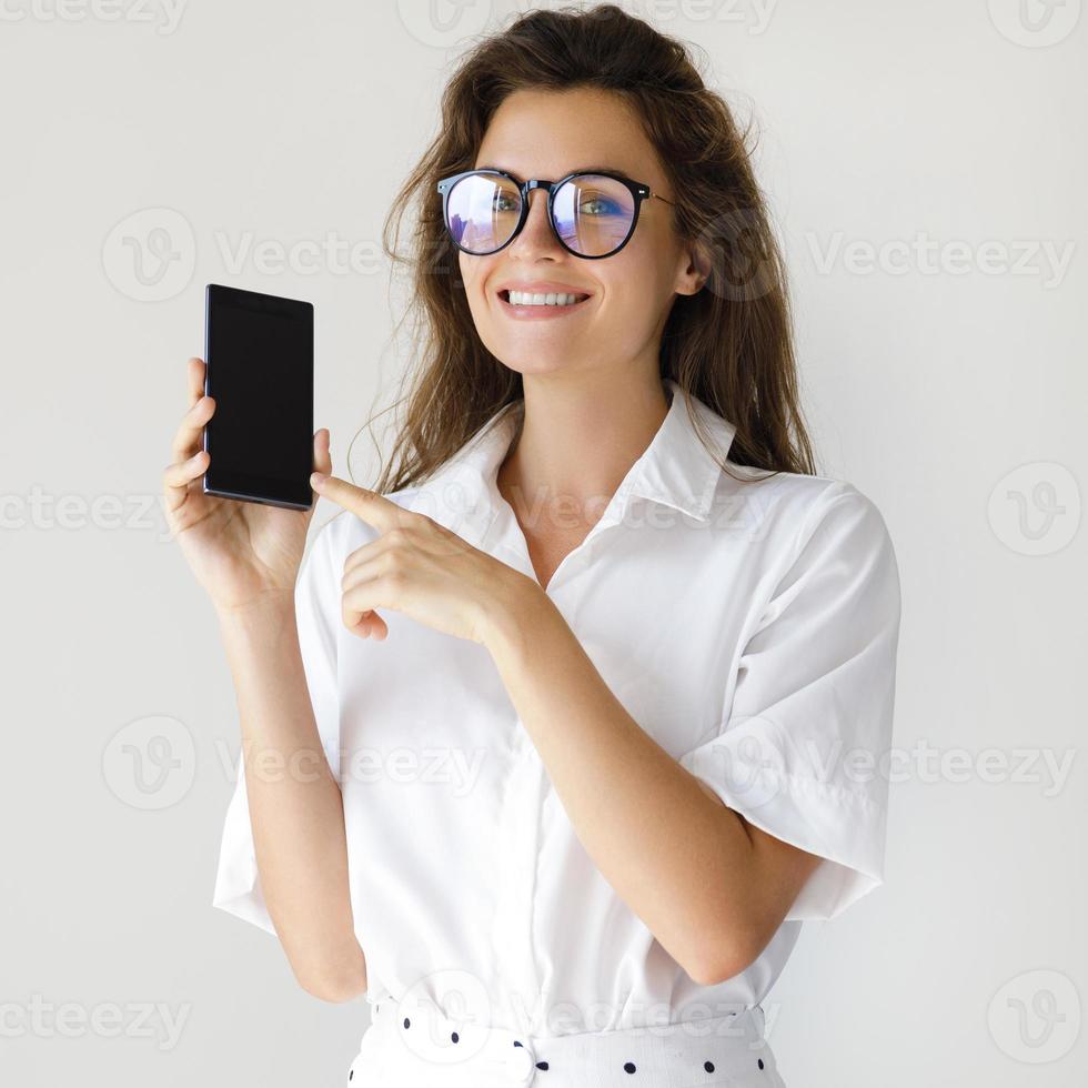 Businesswoman showing smartphone display on gray background photo