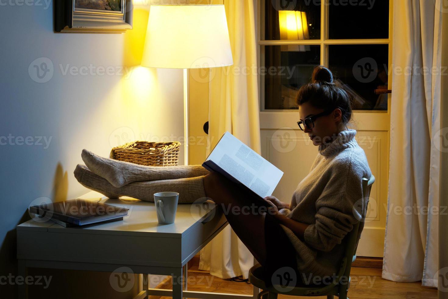 Woman wearing a warm woolen sweater is reading book photo