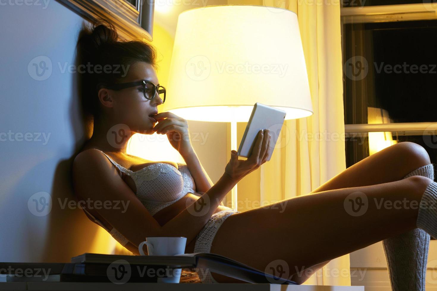 Sexy woman in lingerie is using tablet at late night photo