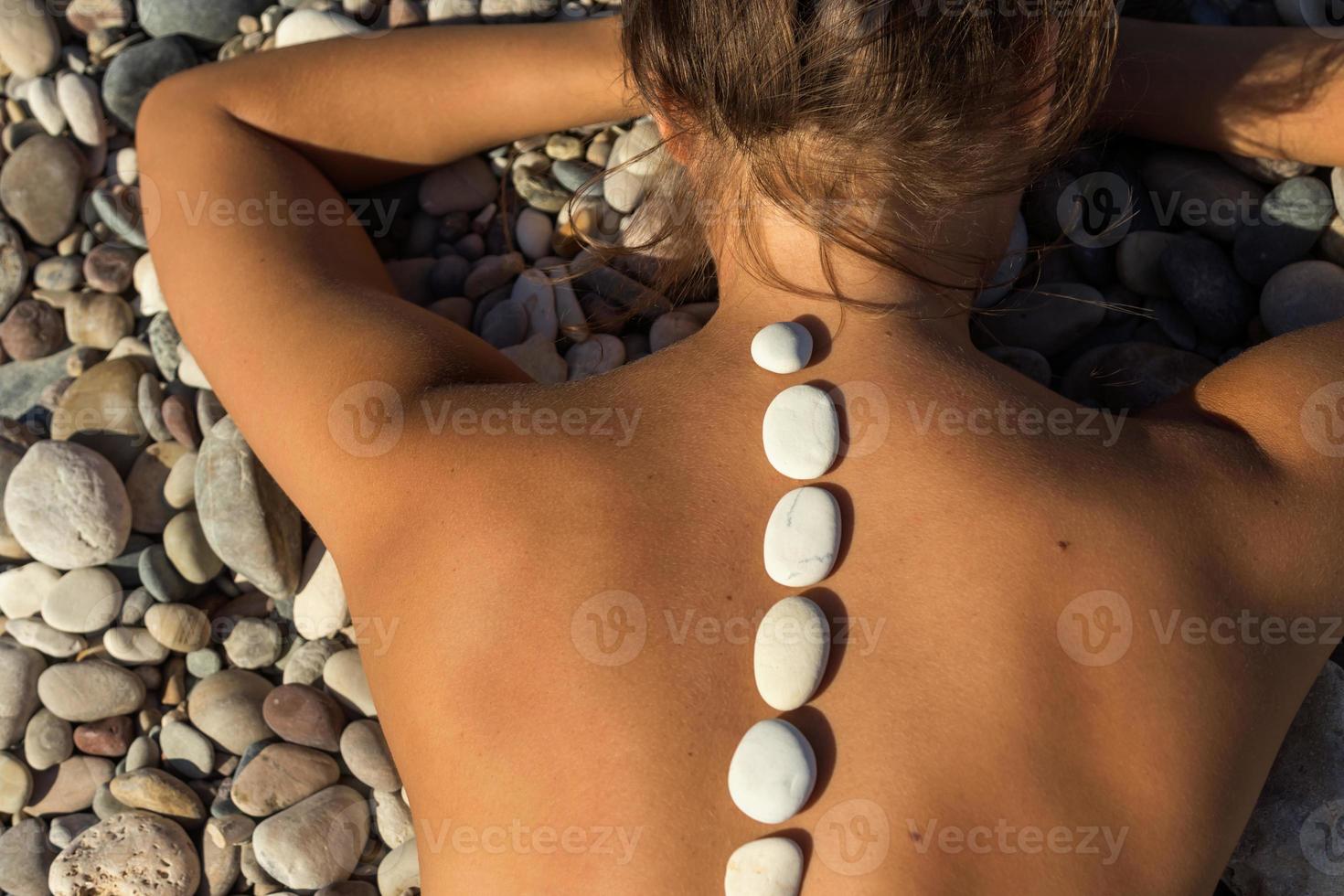 la mujer está acostada con piedras calientes en la espalda foto