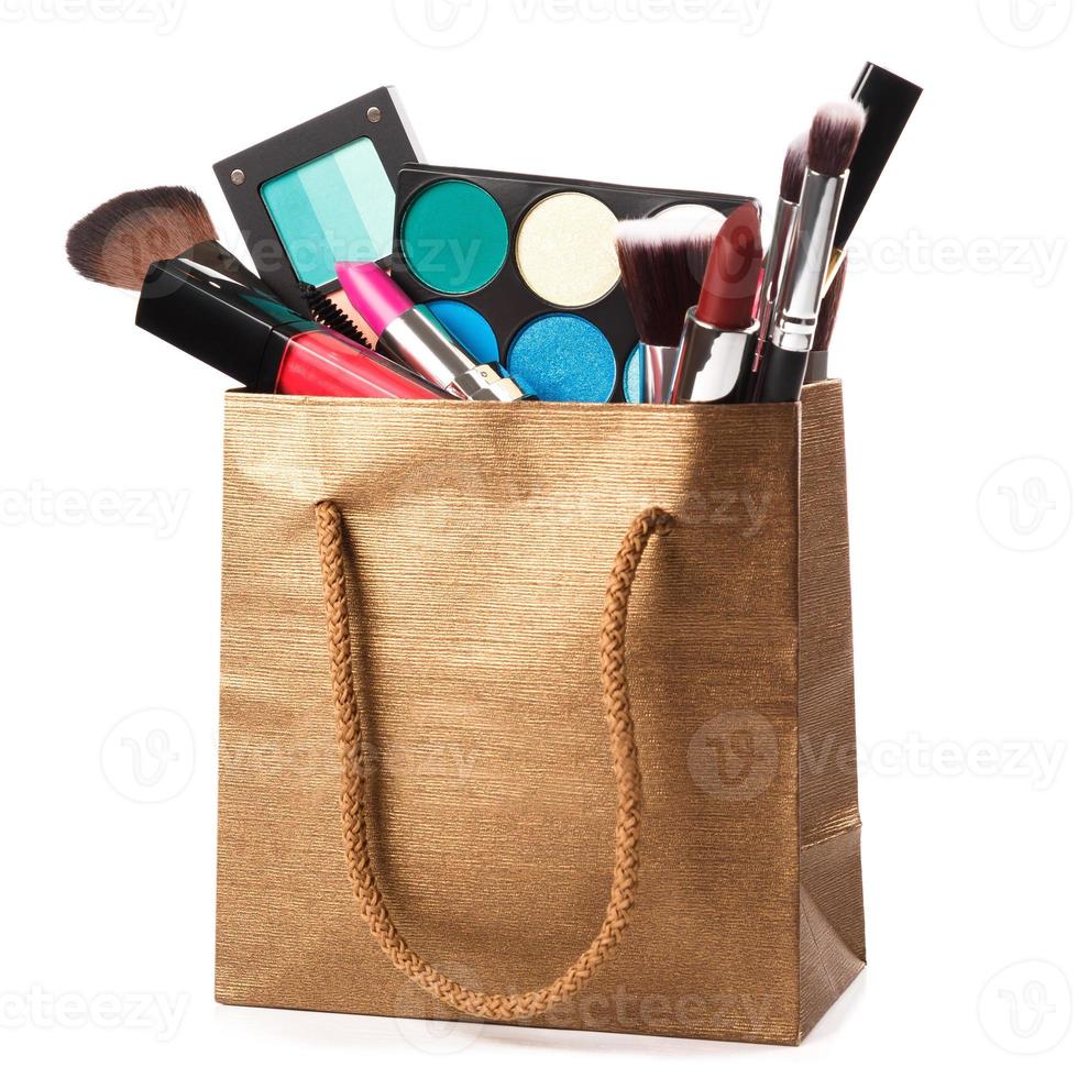 Different makeup objects in shopping bag on white photo