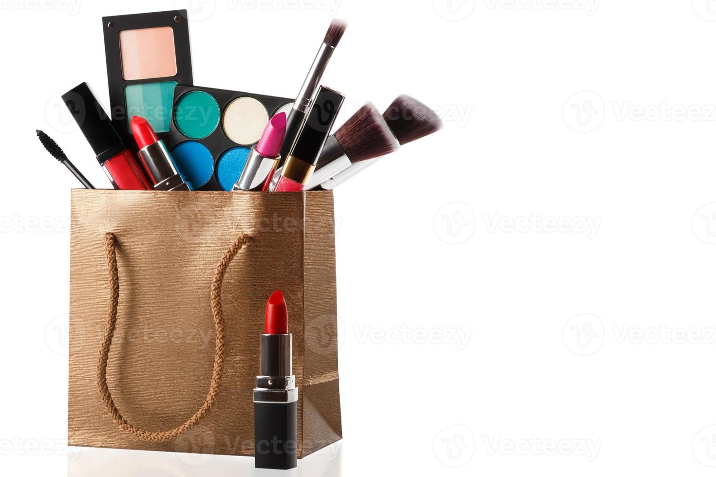 Different makeup objects in shopping bag on white photo