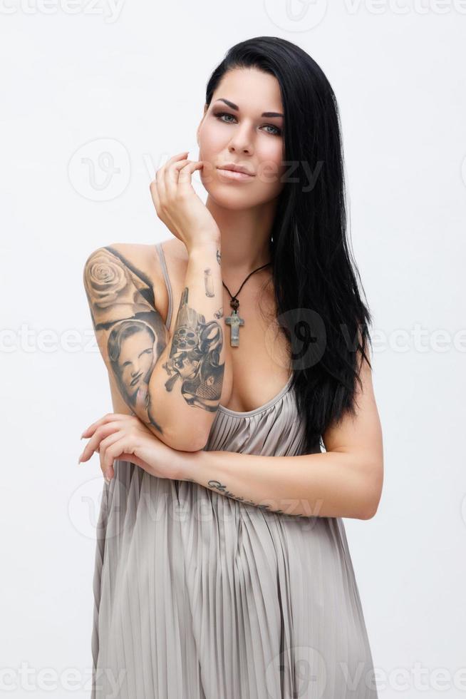Woman with tattoos wearing beautiful dress in studio photo