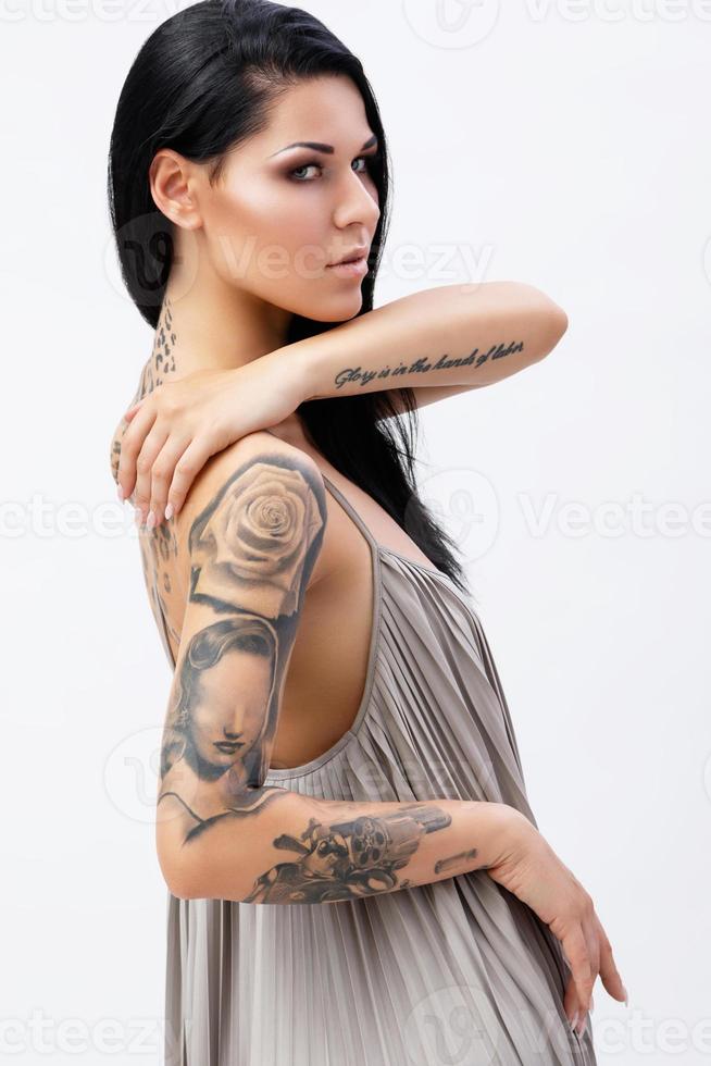 Woman with tattoos wearing beautiful dress in studio photo