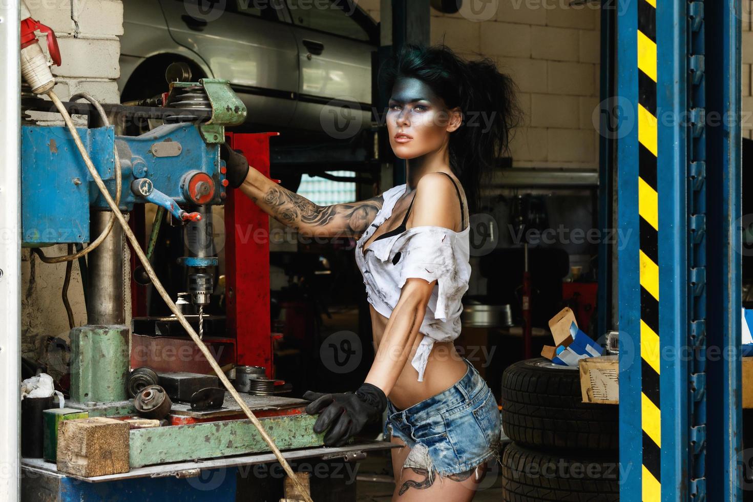 Female mechanic in the garage with artistic makeup on her face stylized like a dirty spot photo