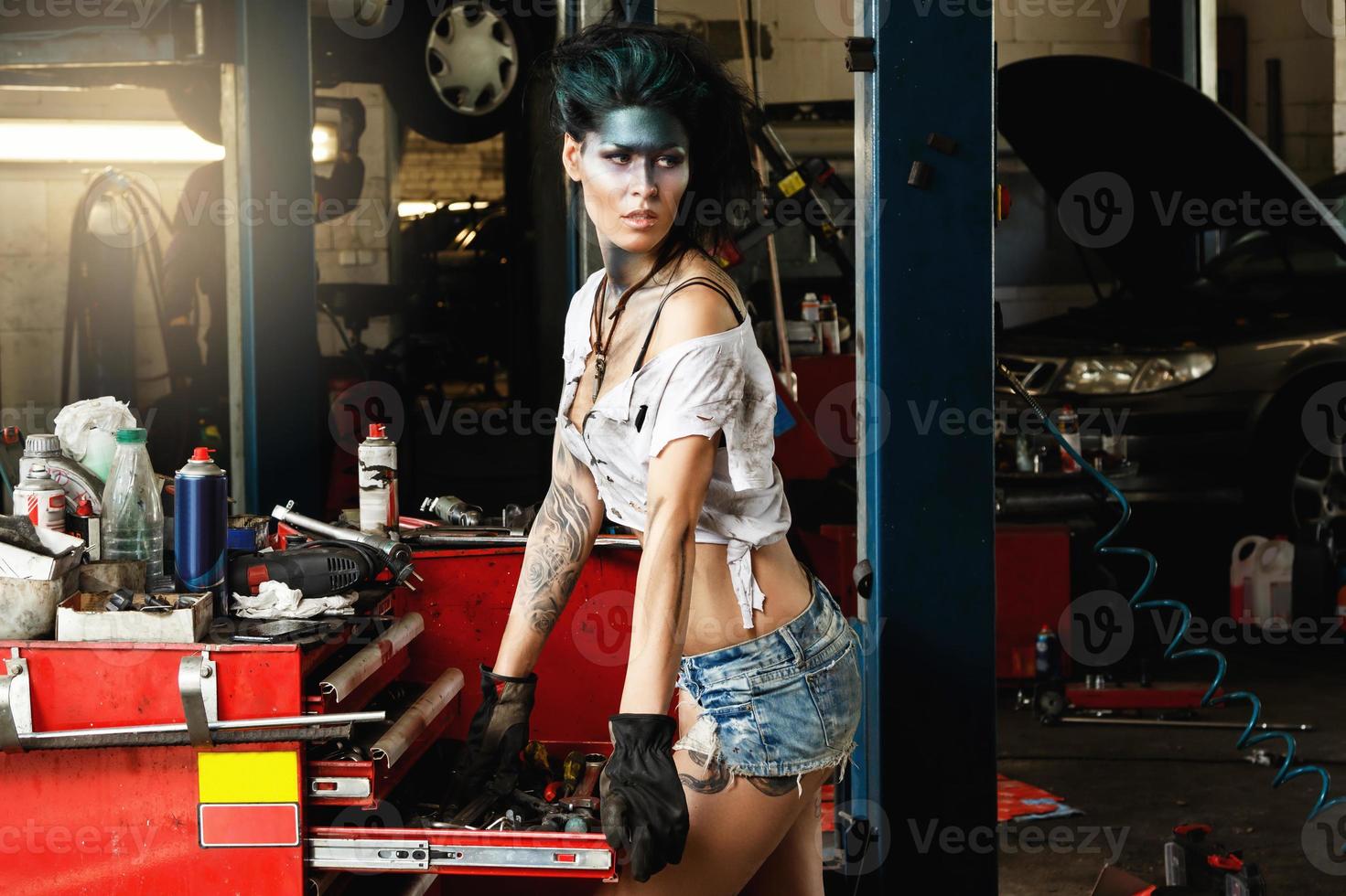 Female mechanic in the garage with artistic makeup on her face stylized like a dirty spot photo