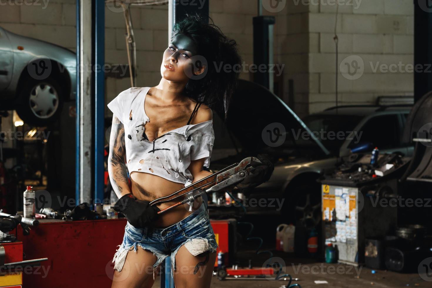 Female mechanic in the garage with artistic makeup on her face stylized like a dirty spot photo