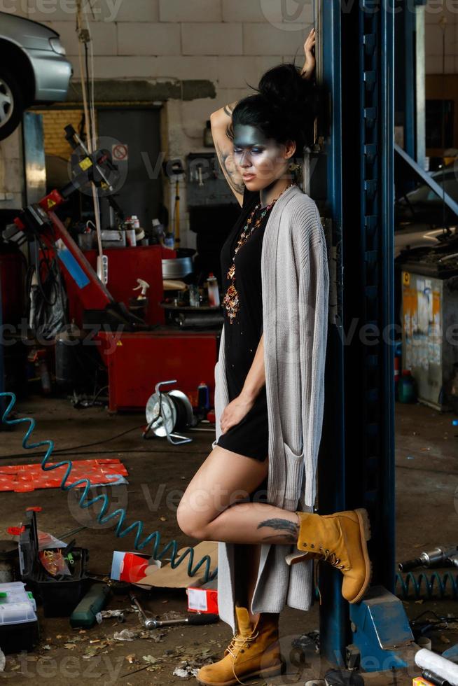 Female mechanic in the garage with artistic makeup on her face stylized like a dirty spot photo