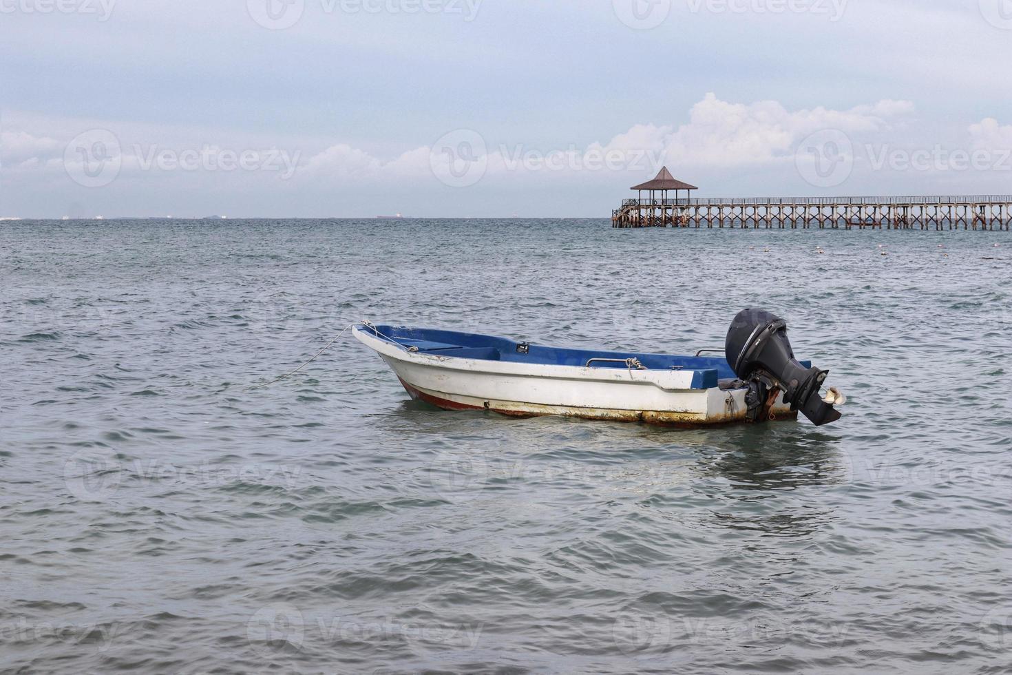 Small white paint motor boat and blue paint inside with nobody inside floating somewhere at the sea. photo