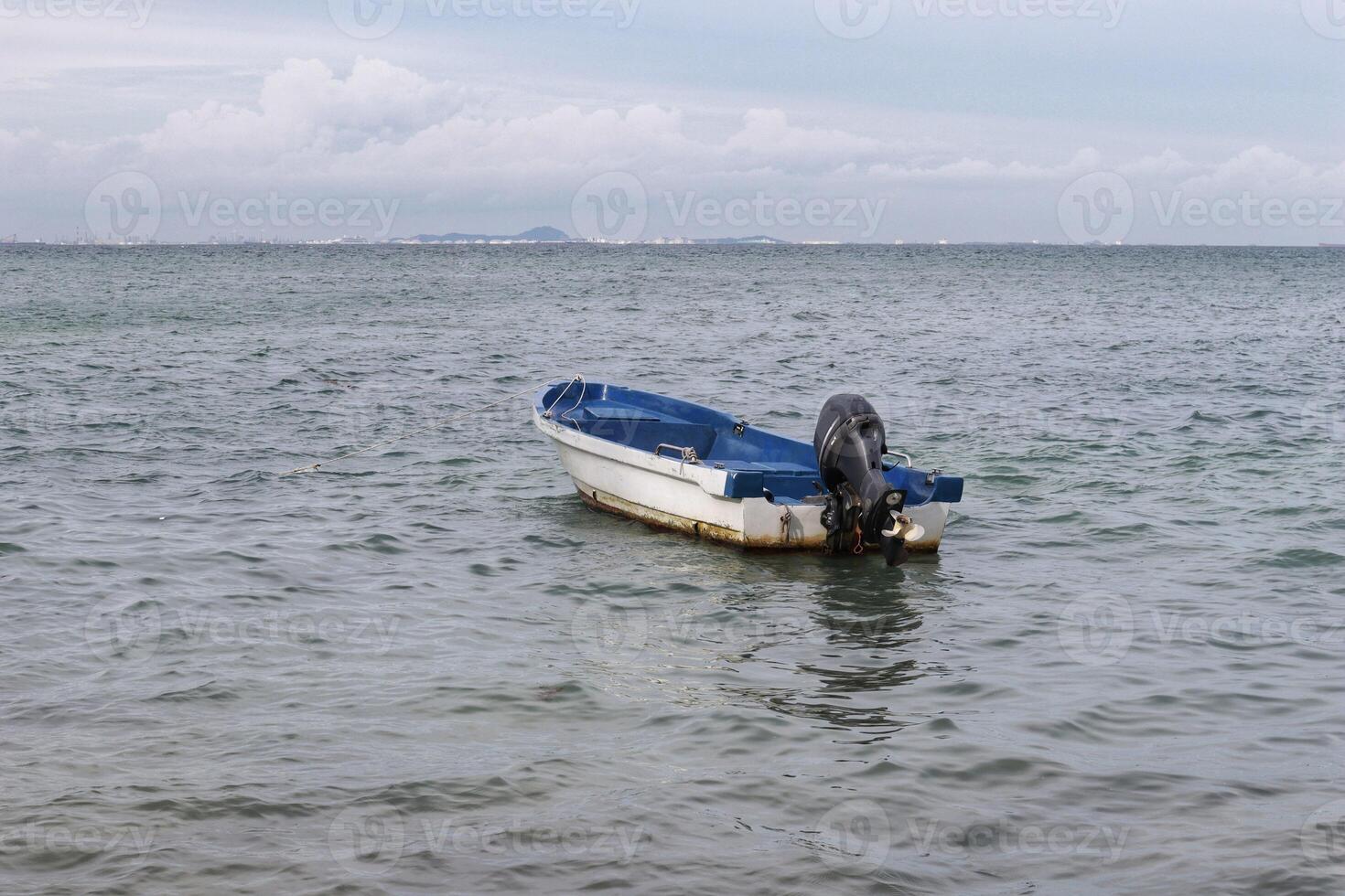 Small white paint motor boat and blue paint inside with nobody inside floating somewhere at the sea. photo