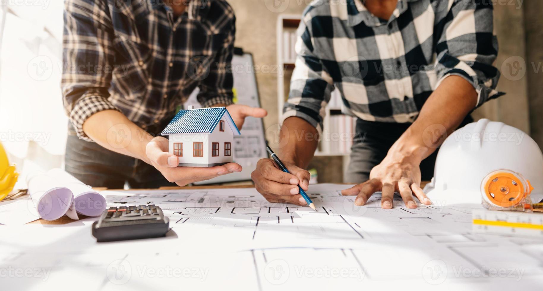 Scale model house on table with architects. Two architects making architectural model in office together. to form a new buildin photo