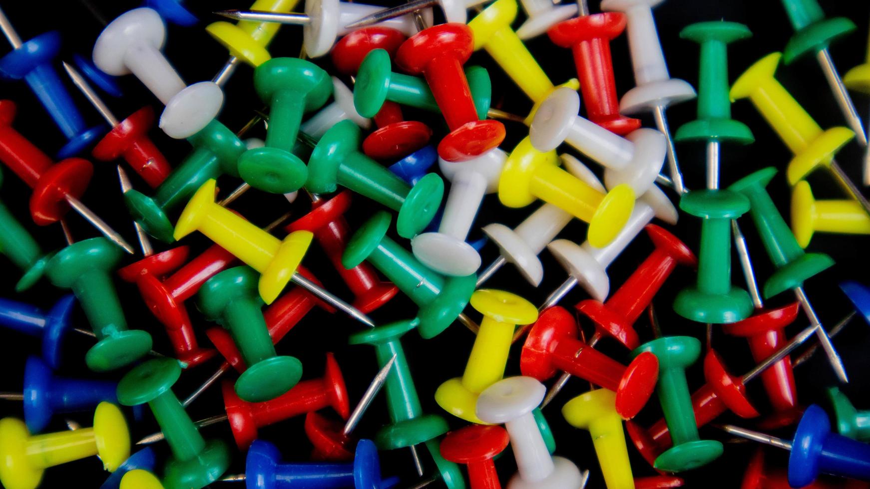 multicolored thumbtacks on a black background photo