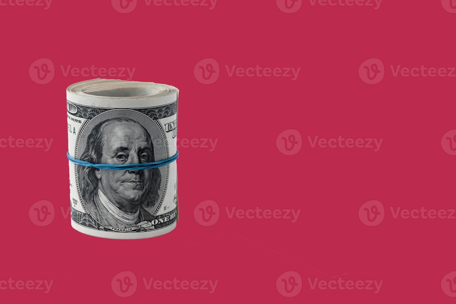 Roll of Paper money, background of one hundred dollar bills on a carmine red background. copy space. photo