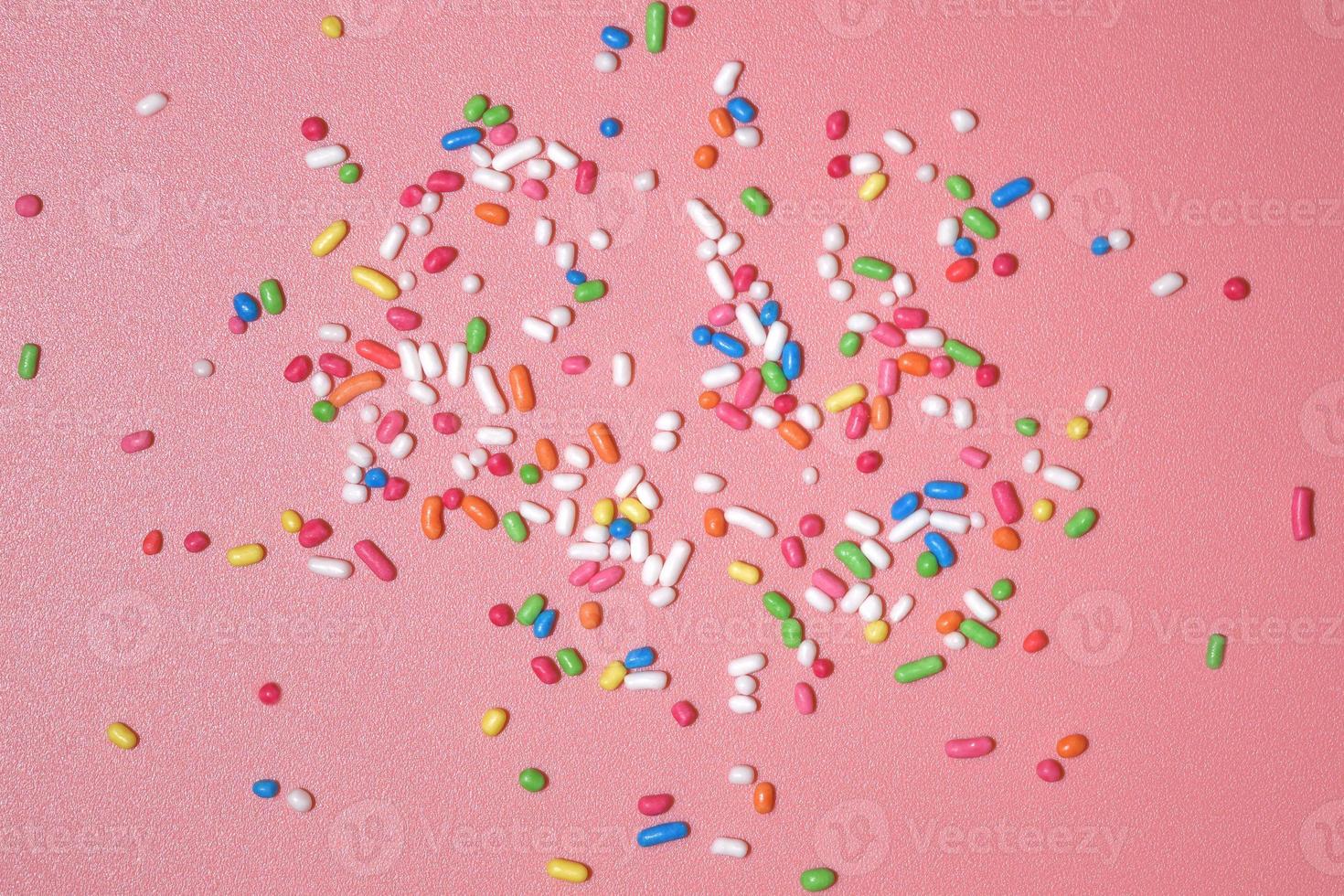 Colorful sprinkles over pink background, decoration for cake and bakery photo