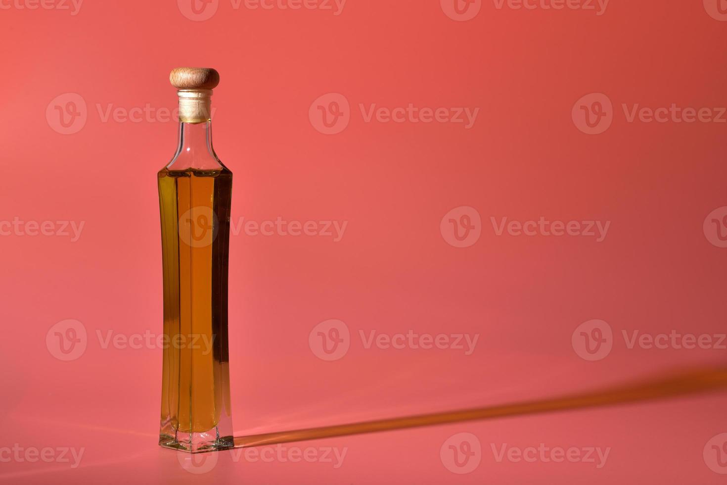 Edible oil in glass bottle isolated on pink background photo