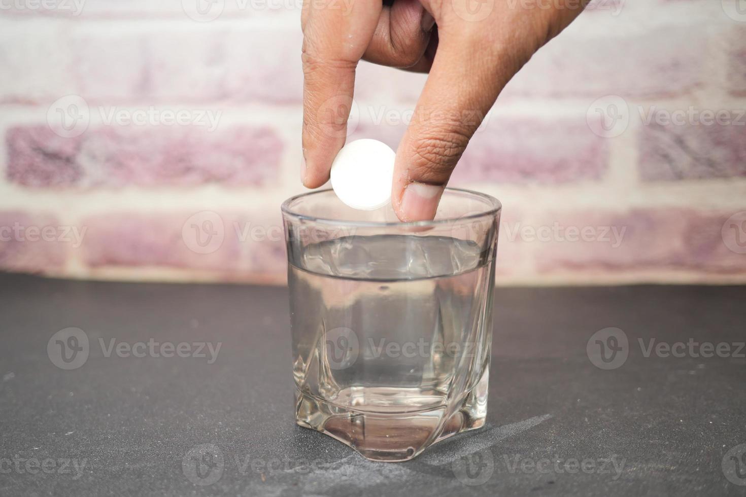 dropping Effervescent soluble tablet pills in a glass of water photo