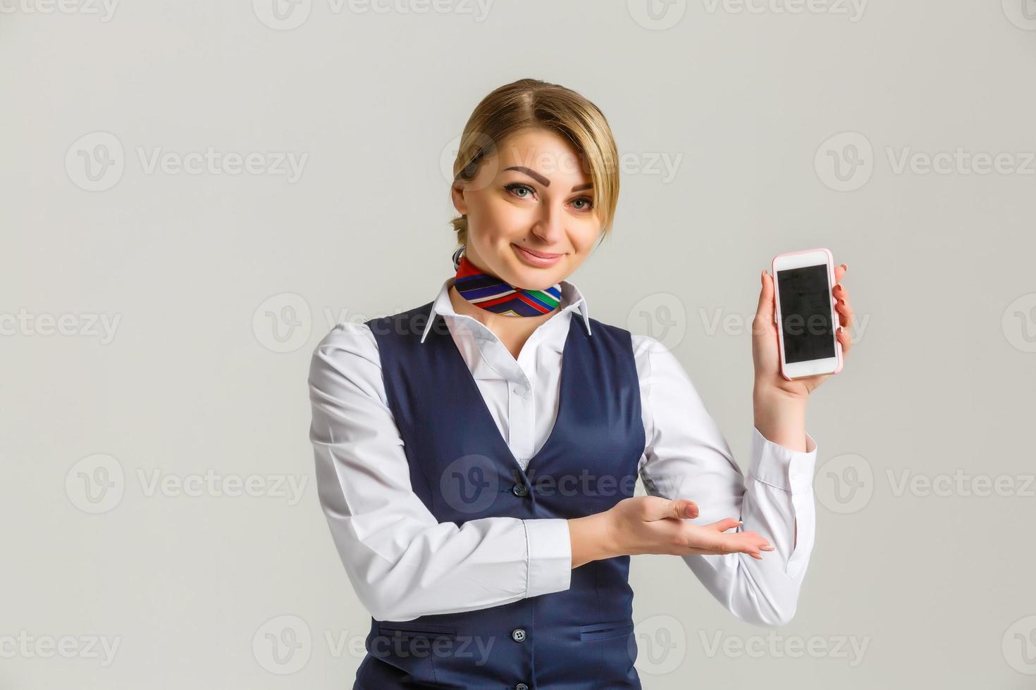 Beautiful young stewardess holding a smart phone isolated on white background photo