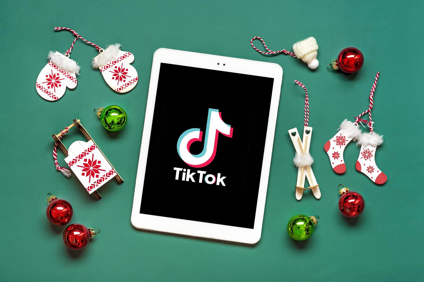 Bangkok, Thailand. December 2022 Smartphone Tik Tok application icon, logo on screen, wireless headphones on green background Trendy social media network concept Flat lay Top view New year, Christmas photo