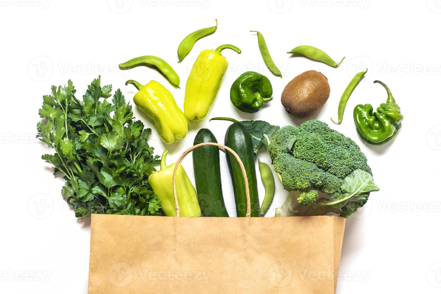 Eco friendly paper shop bag with raw organic green vegetables isolated on white background Flat lay, top view Zero waste, plastic free concept Healthy clean eating diet and detox, agriculture concept photo