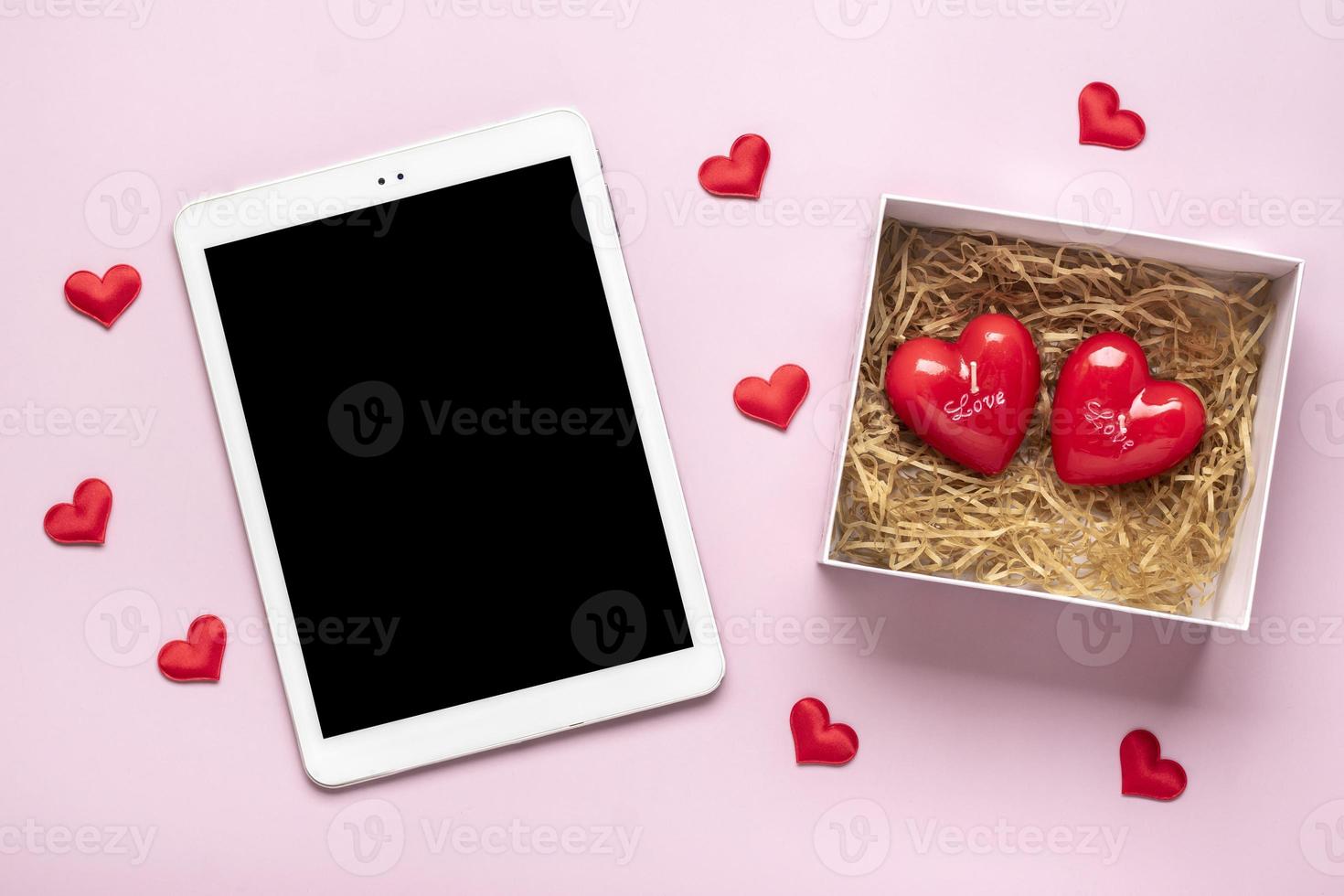 tableta digital para elegir regalos, hacer compras, sobres, corazones rojos en la vista superior de la mesa rosa lista de compras navideñas planas, feliz día de san valentín, fiesta, concepto de tienda en línea maqueta foto