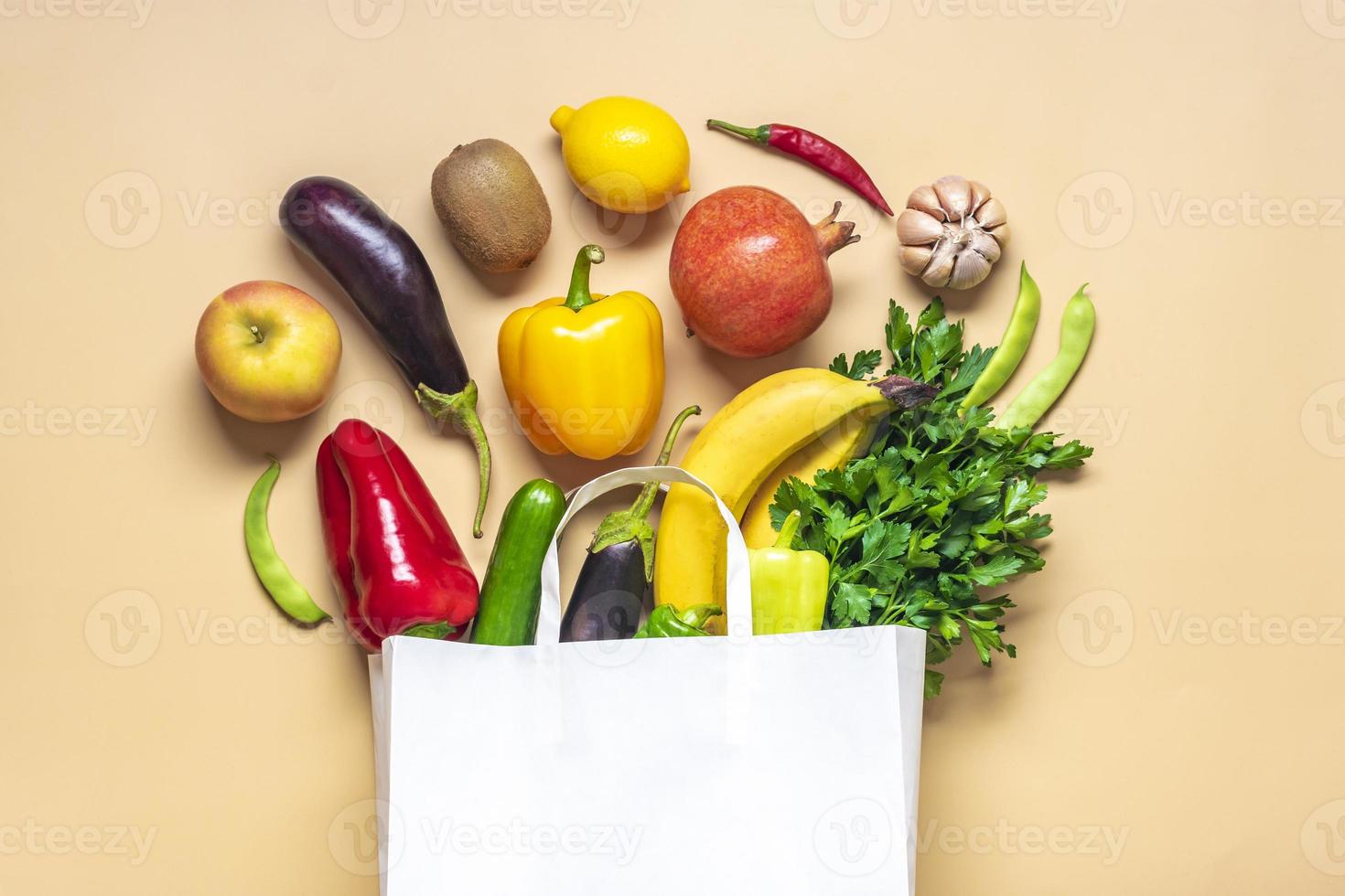 Eco friendly paper shop bag with raw organic green vegetables isolated on beige background Flat lay, top view Zero waste, plastic free concept Healthy clean eating diet and detox, agriculture concept photo