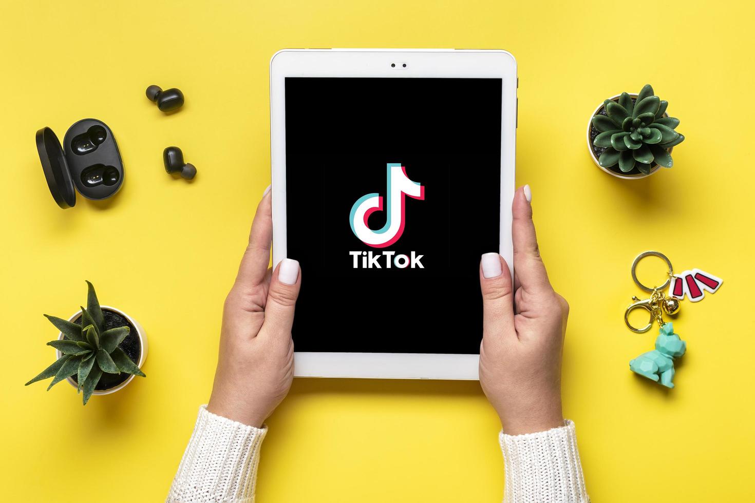 Bangkok, Tailandia. octubre de 2022 icono de la aplicación tik tok de la tableta, logotipo en pantalla y auriculares inalámbricos sobre fondo colorido concepto de red social de moda vista plana superior foto