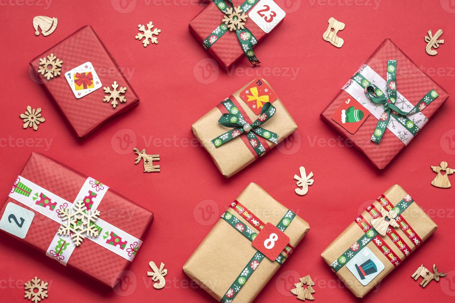 Handmade wrapped red, green gift boxes decorated with ribbons, snowflakes and numbers, Christmas decorations and decor on red table Xmas advent calendar concept Top view Flat lay Holiday card photo