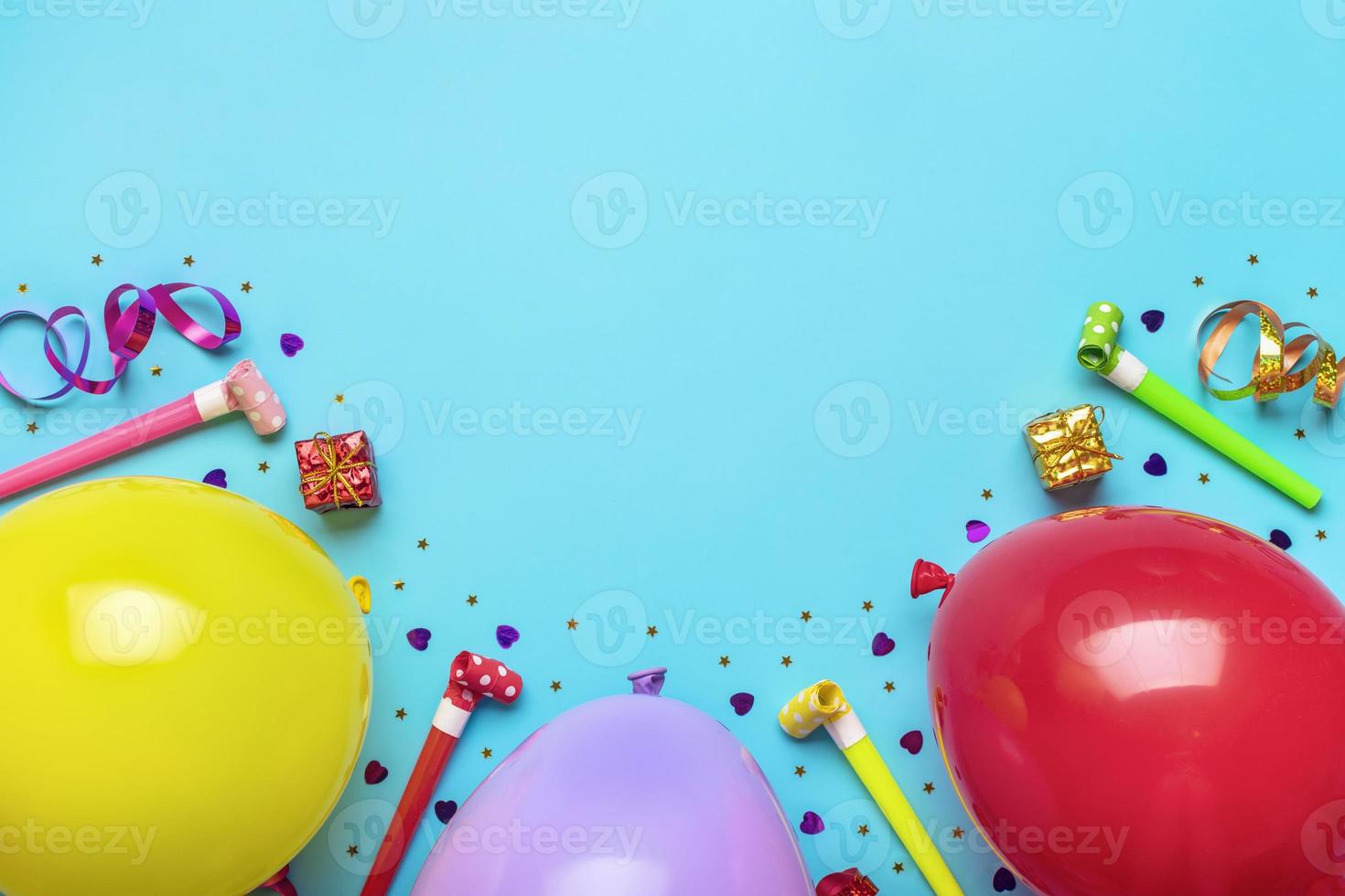 Colorful party frame with red gift box with various party confetti, balloons, streamers, pokers and decorations on blue background. Holiday card Flat lay Top view Happy Birthday party concept photo