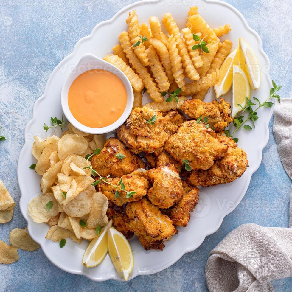 pescado y papas fritas en un plato para servir con salsa para mojar foto