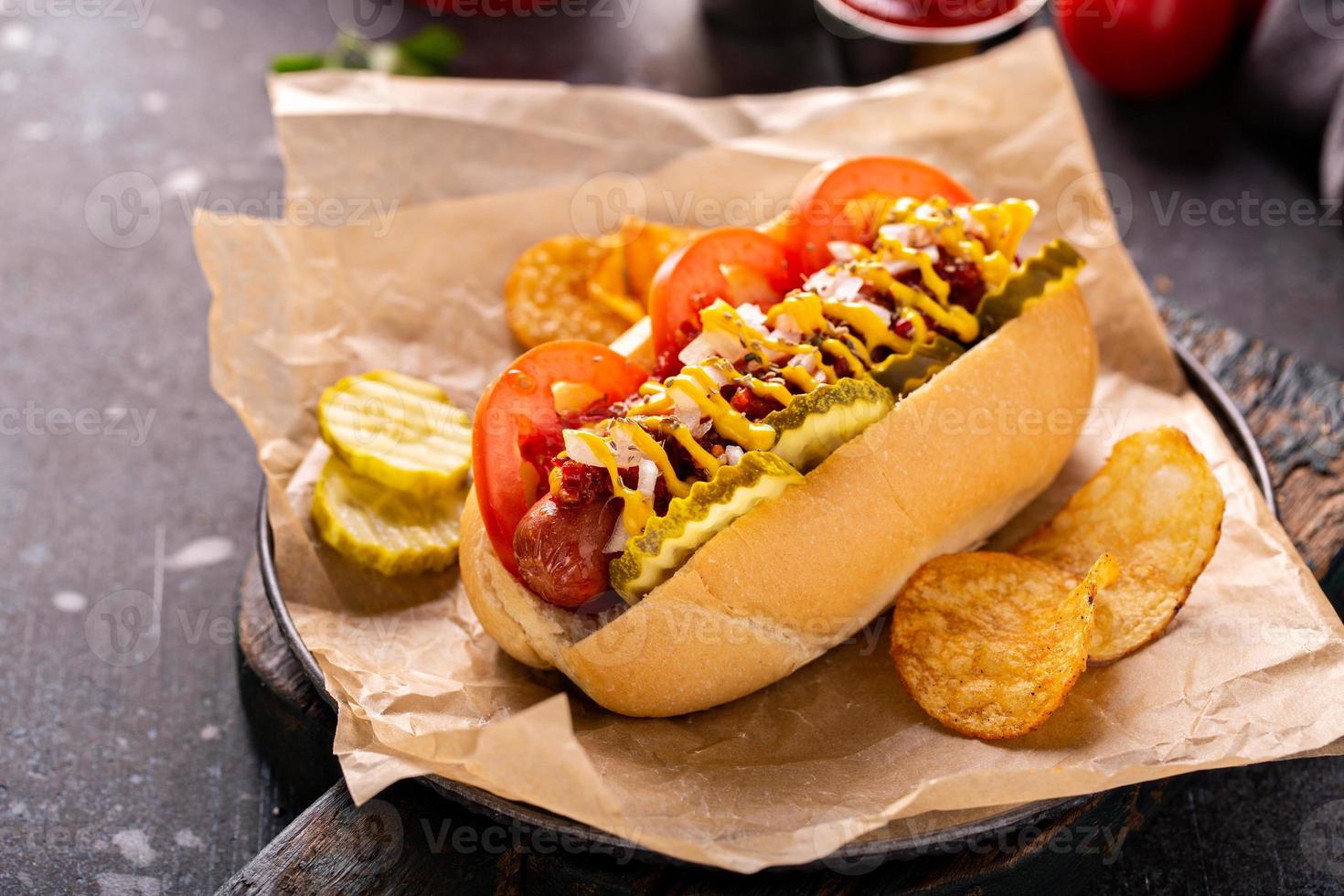 Hot dog with tomatoes, mustard and pickles photo