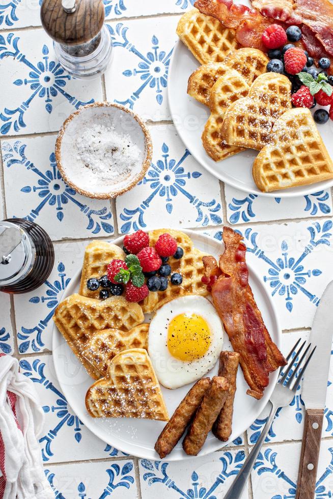 Breakfast table with waffles. fried egg, bacon and sausage photo