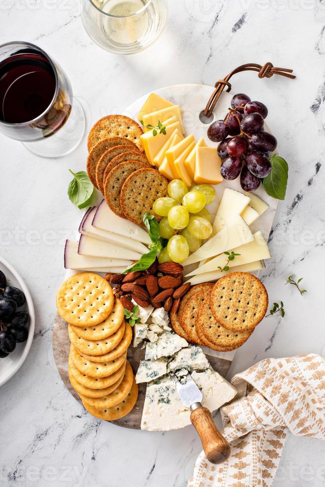 tabla de quesos con galletas, nueces y uvas foto