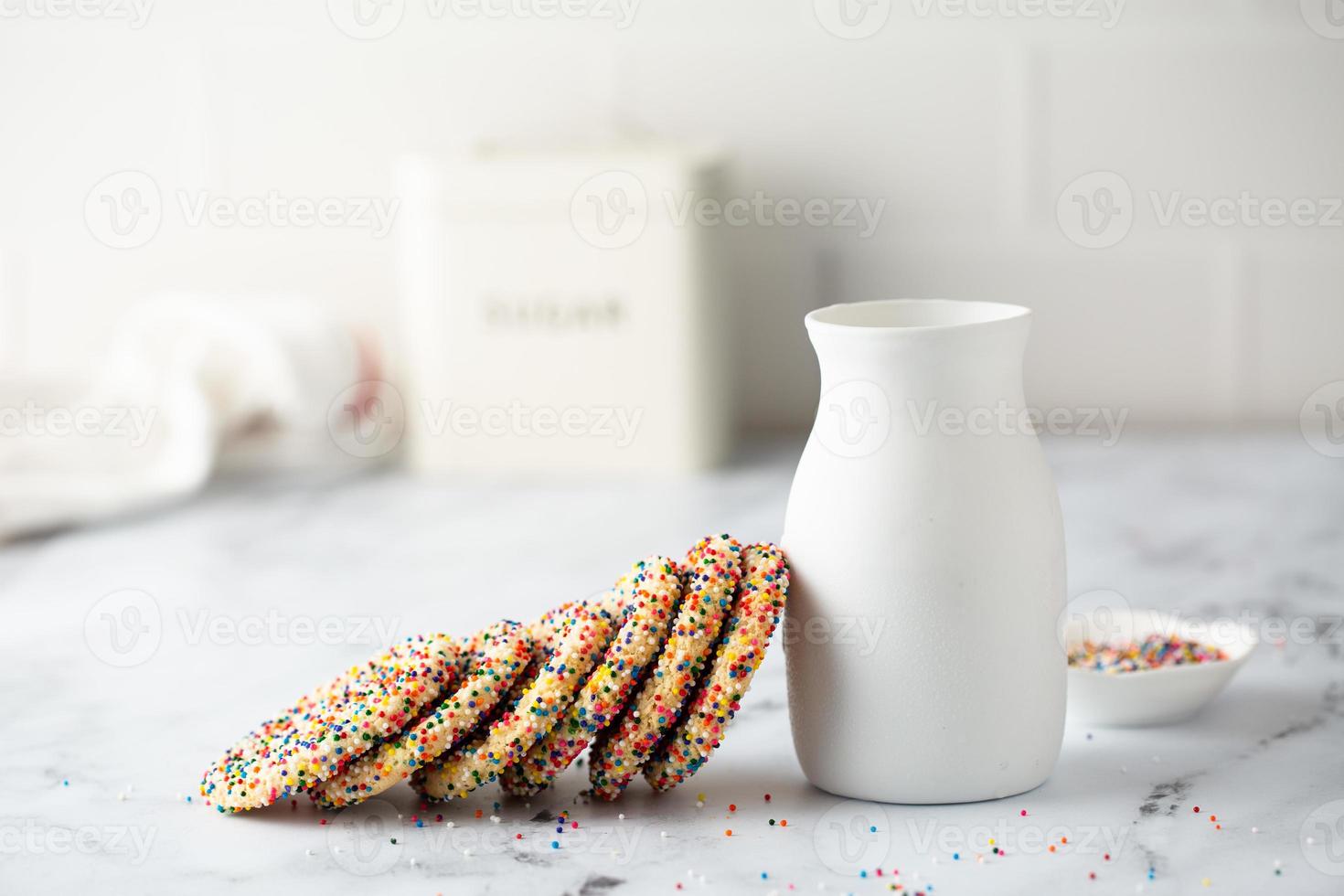 Sugar cookies with sprinkles and a bottle of milk photo