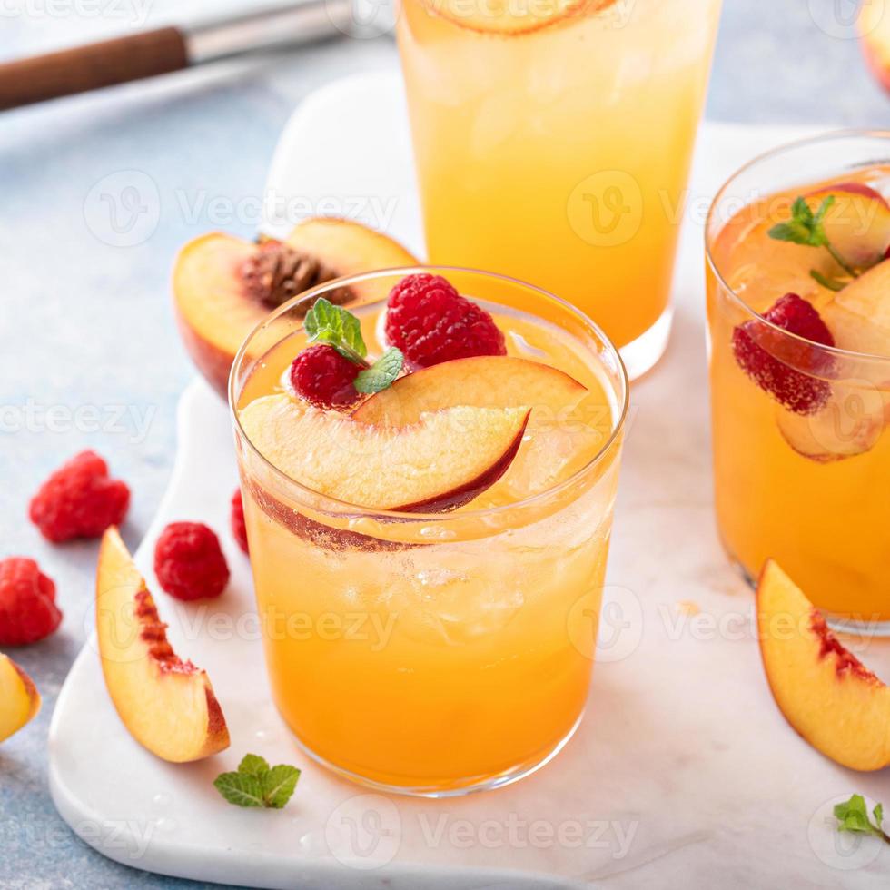 Refreshing summer cocktail with peach and raspberry photo