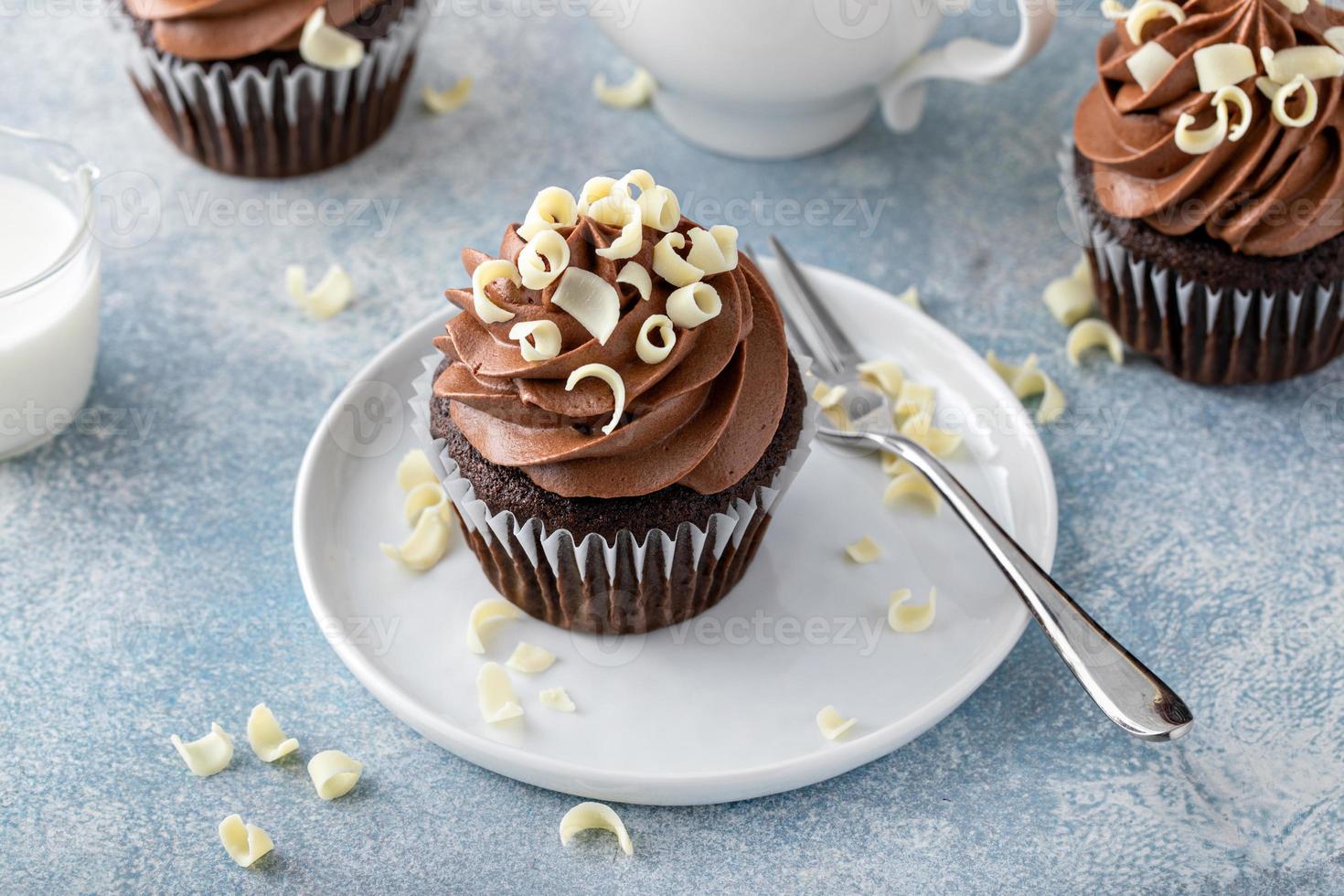 Dark chocolate cupcakes with whipped ganache frosting and white chocolate curls photo