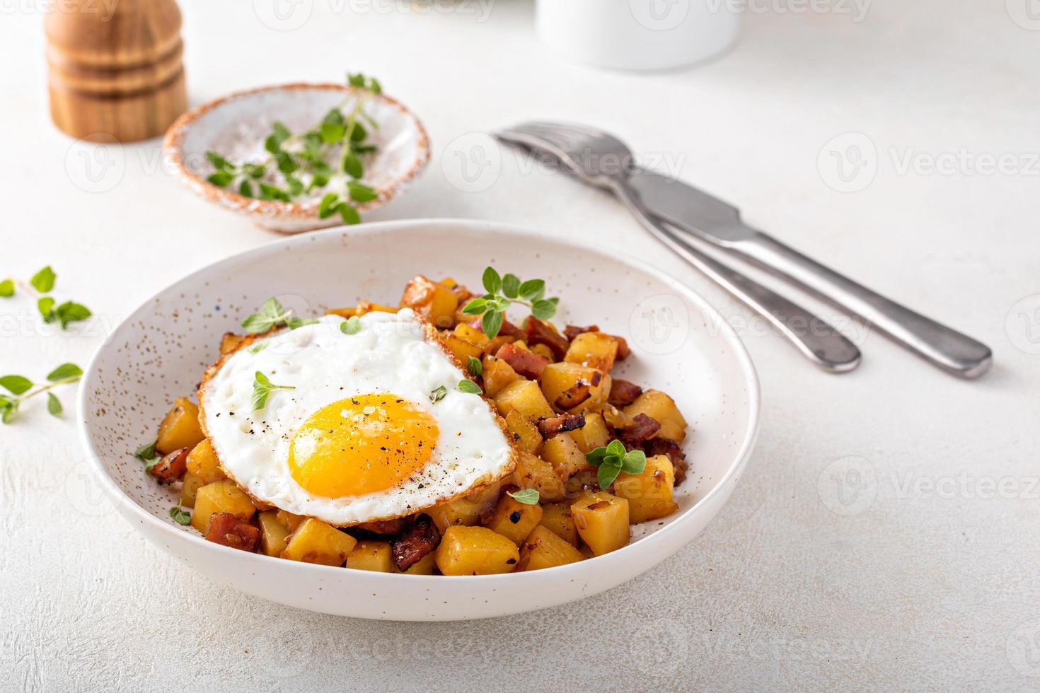 Potato, onion and ham hash topped with fried egg photo