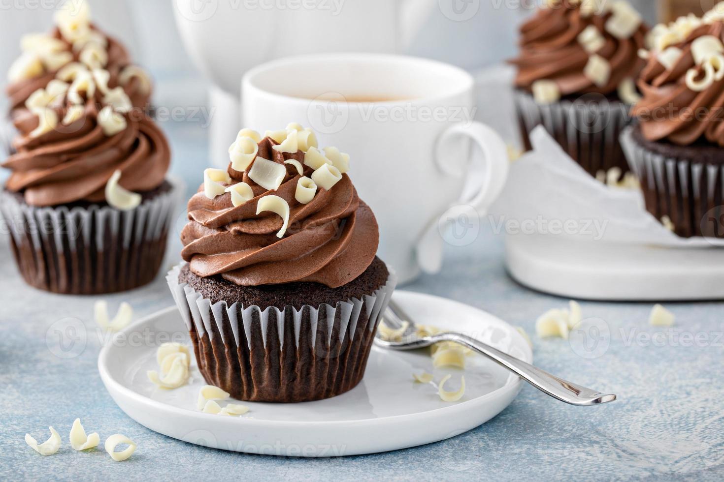 Dark chocolate cupcakes with whipped ganache frosting and white chocolate curls photo