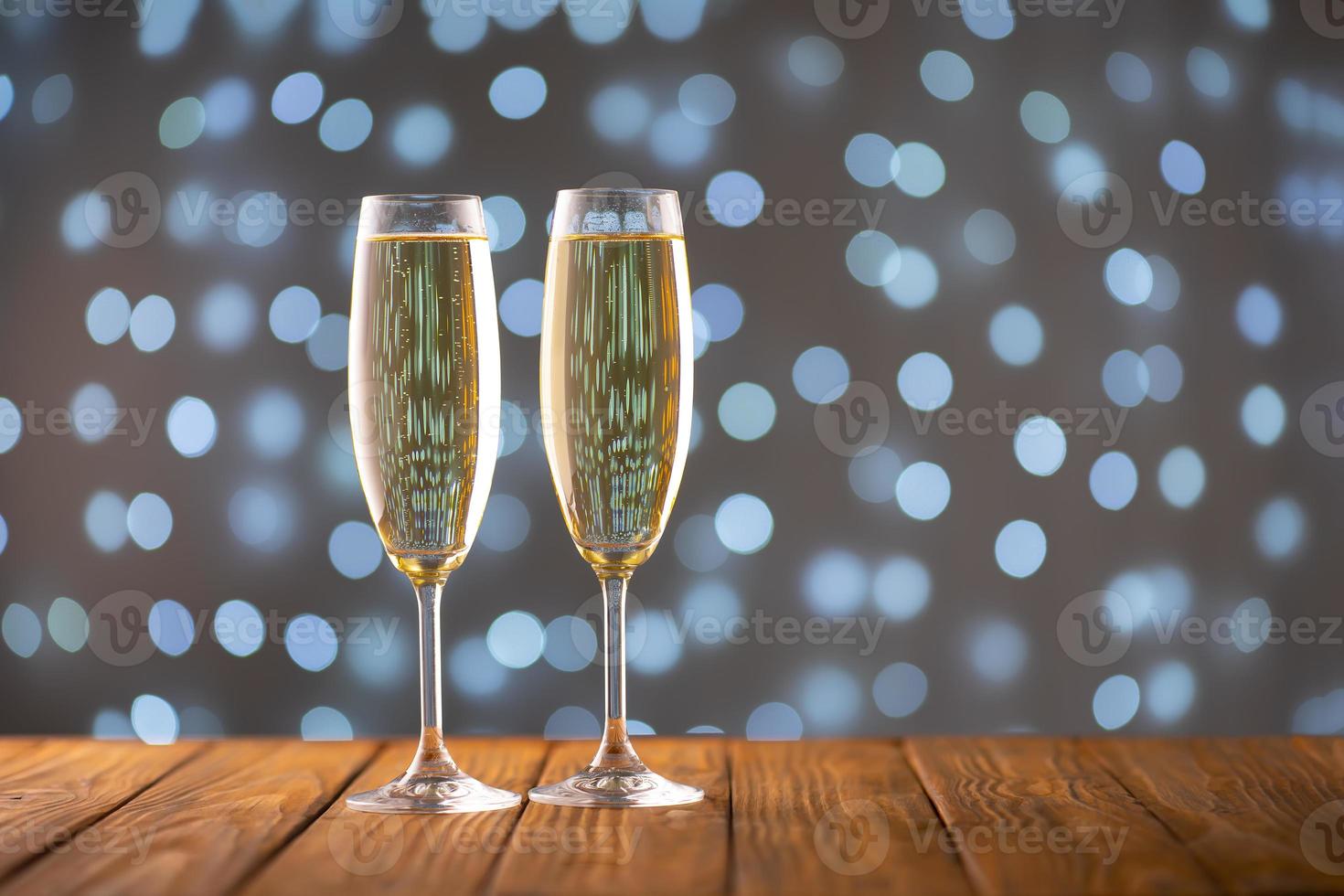 Two wine glasses with bubbly Champagne on blurry sparkling lights background photo