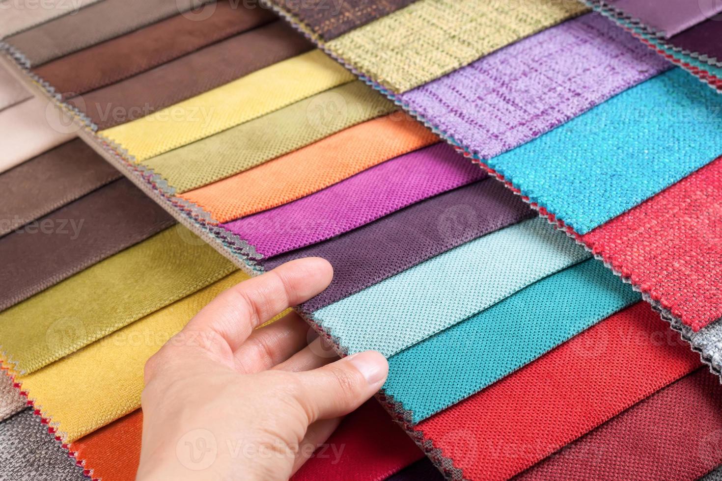 Woman hand chooses samples of colored tissue photo