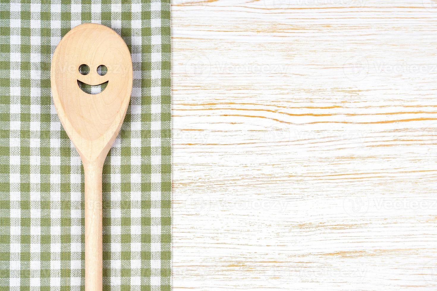 Kitchen mockup. Wooden spoon with smile on white wooden background. Food background with copy space photo