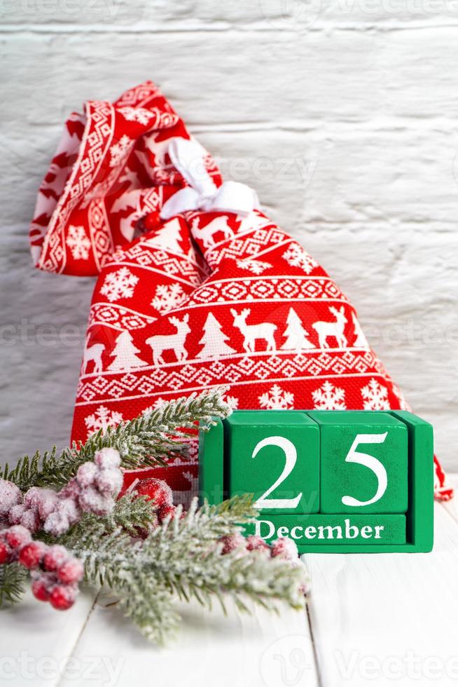 Christmas background with decorated fir tree, red gift bag and green perpetual calendar photo