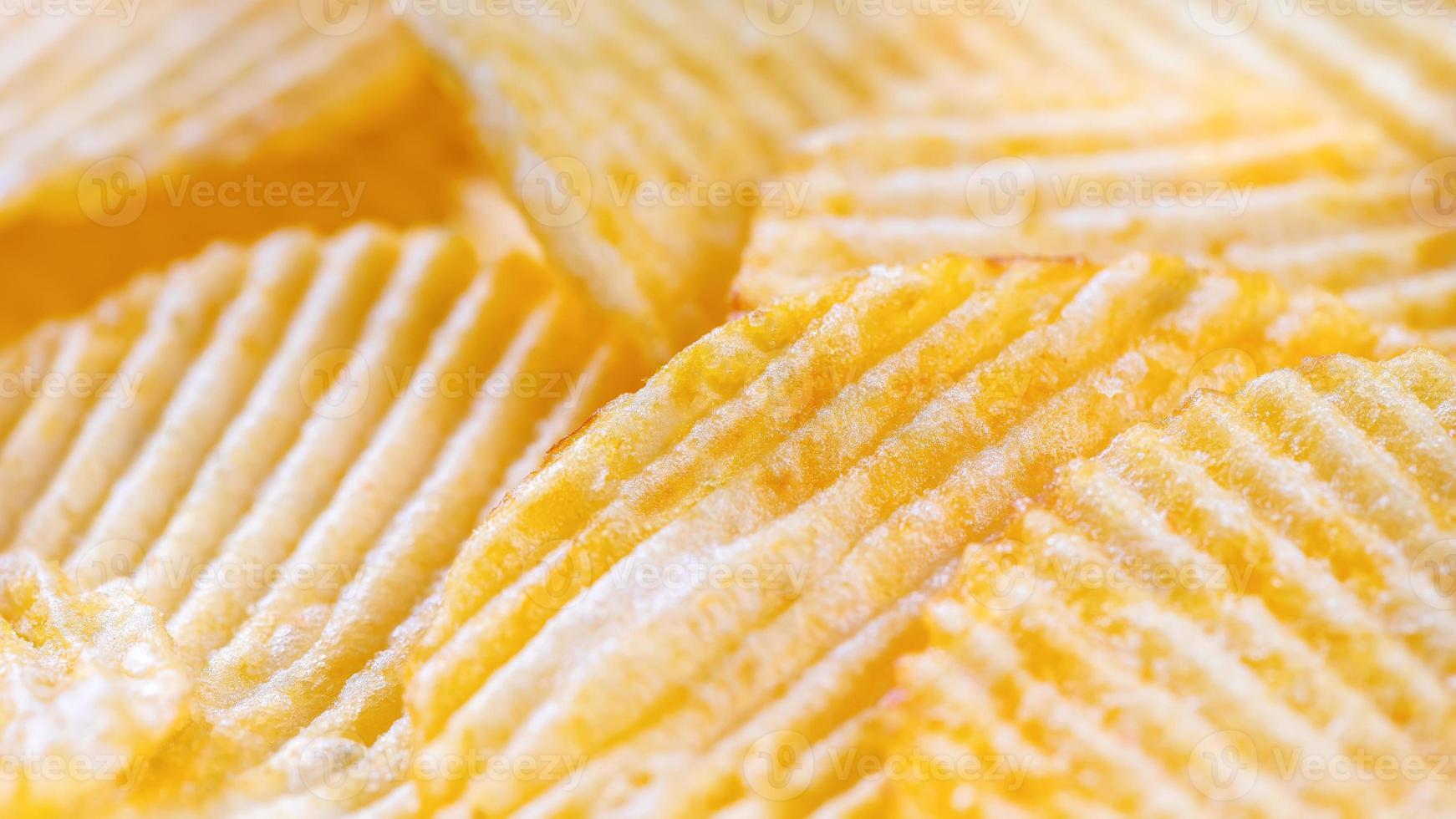 Yellow crispy ridged potato chips close up. Food background photo