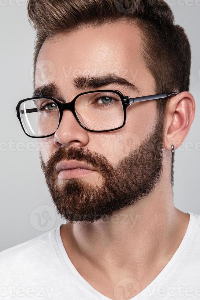 Stylish bearded man in eyeglasses against gray background photo